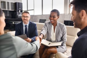 People sitting in office shaking hands at the start of a mediation