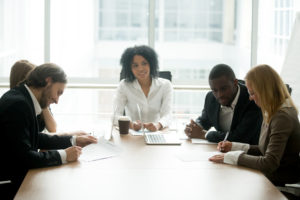 Businessman and businesswoman signing contracts at group multiracial meeting, two smiling male and female new partners signing papers after a mediation