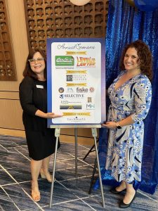 Mediators Brenda Pagliaro and Madeleine Mannello standing near the sponorship sign for the Annual Installation Dinner