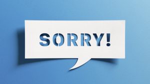 Sorry message to express regret, remorse, apology for error, mistake, guilt and request forgiveness. Concept with word written in cut out paper in shape of speech bubble with blue background.