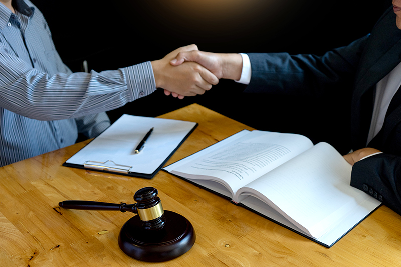 Two people shaking hands in a legal meeting