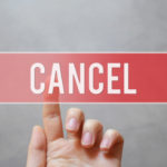A hand pressing red transparent button - CANCEL - on virtual touchscreen interface on grey background