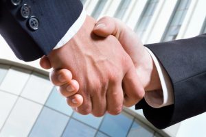Closeup picture of business people shaking hands, making an agreement.