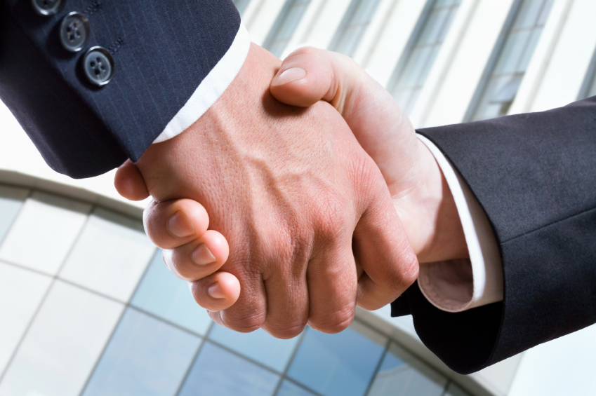 Closeup picture of business people shaking hands, making an agreement.
